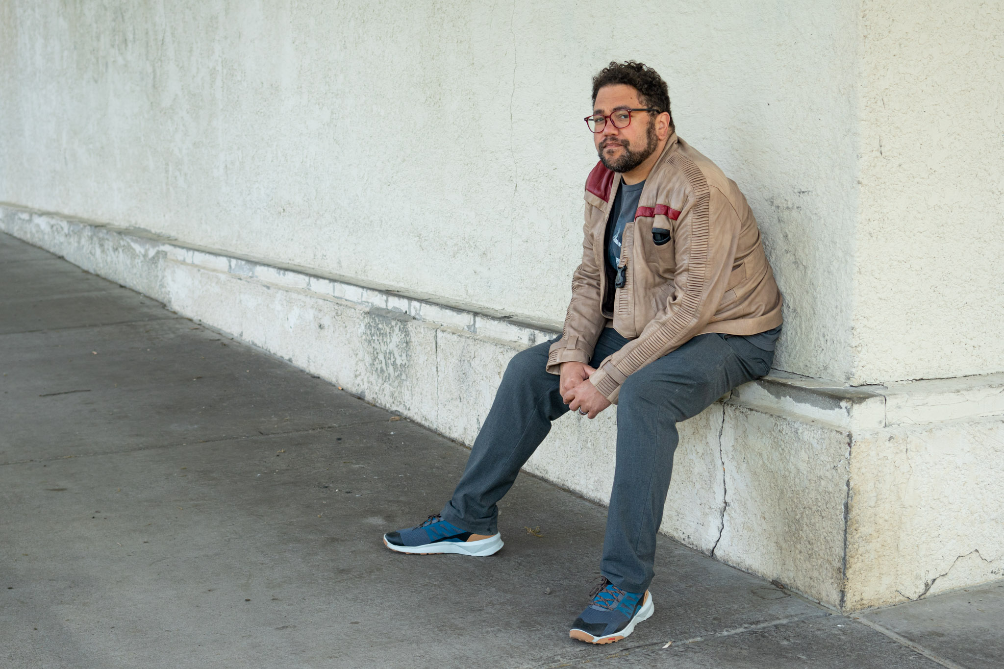 Photo of creator Duck Washington sitting on a curb with a large balnk building behind him.